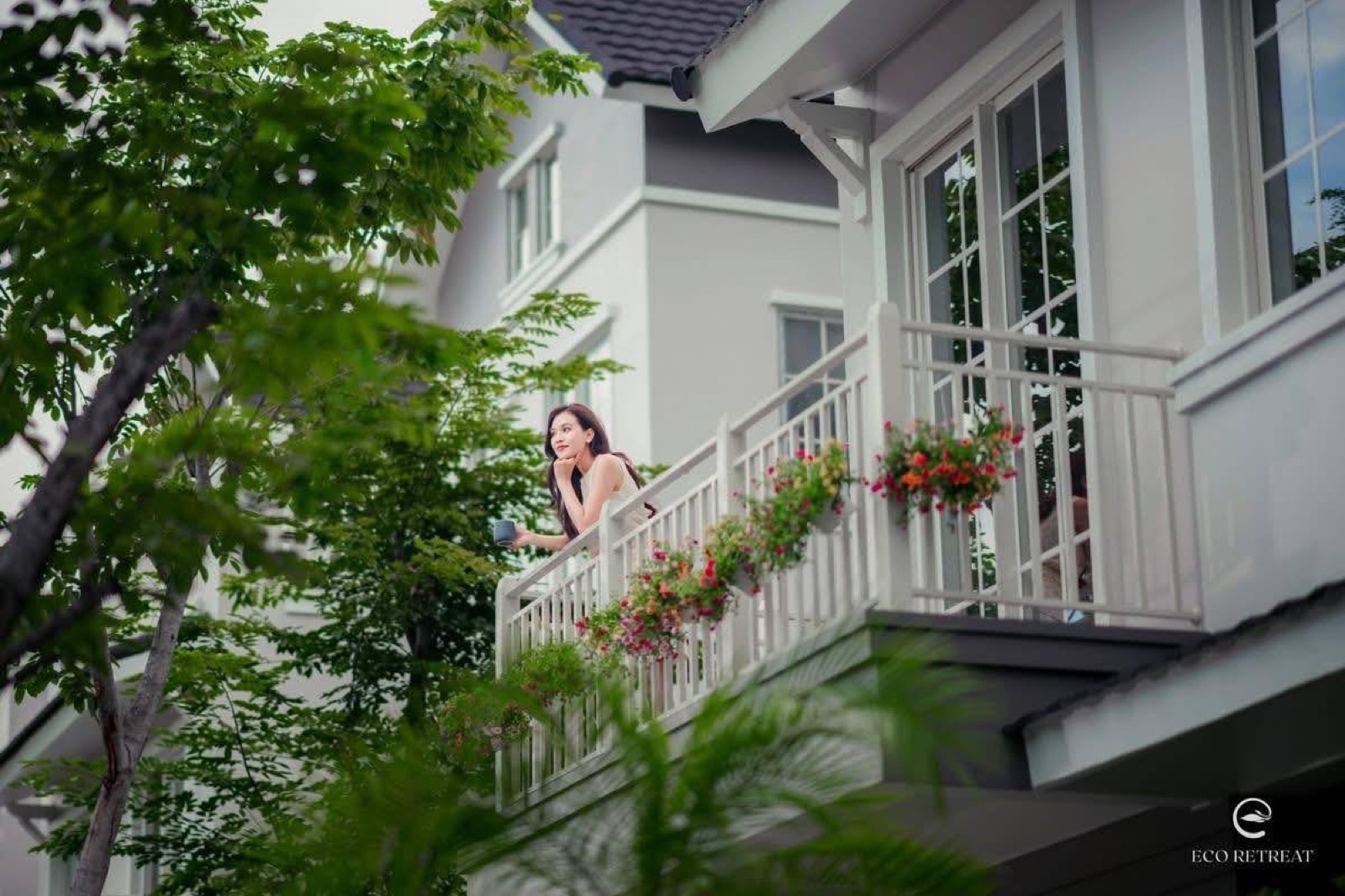 Người phụ nữ đứng trên ban công đầy chậu hoa