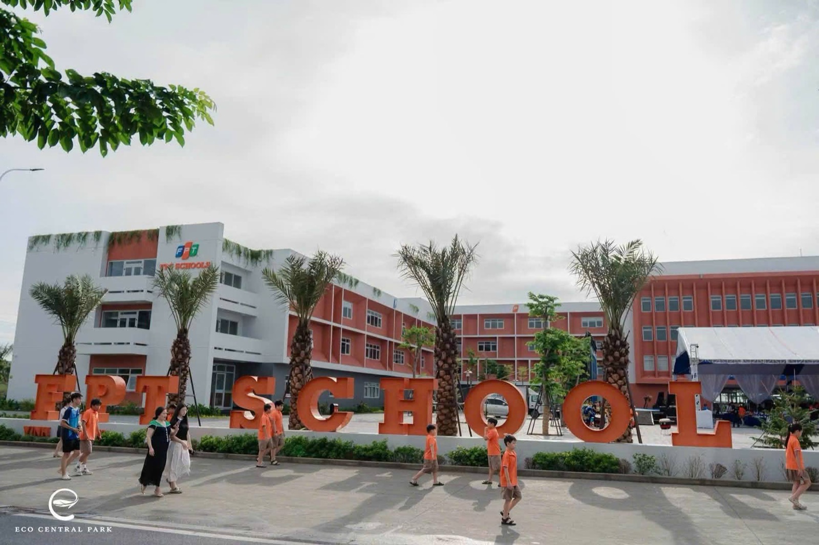 Sân trường với chữ FPT School và hàng cây cọ