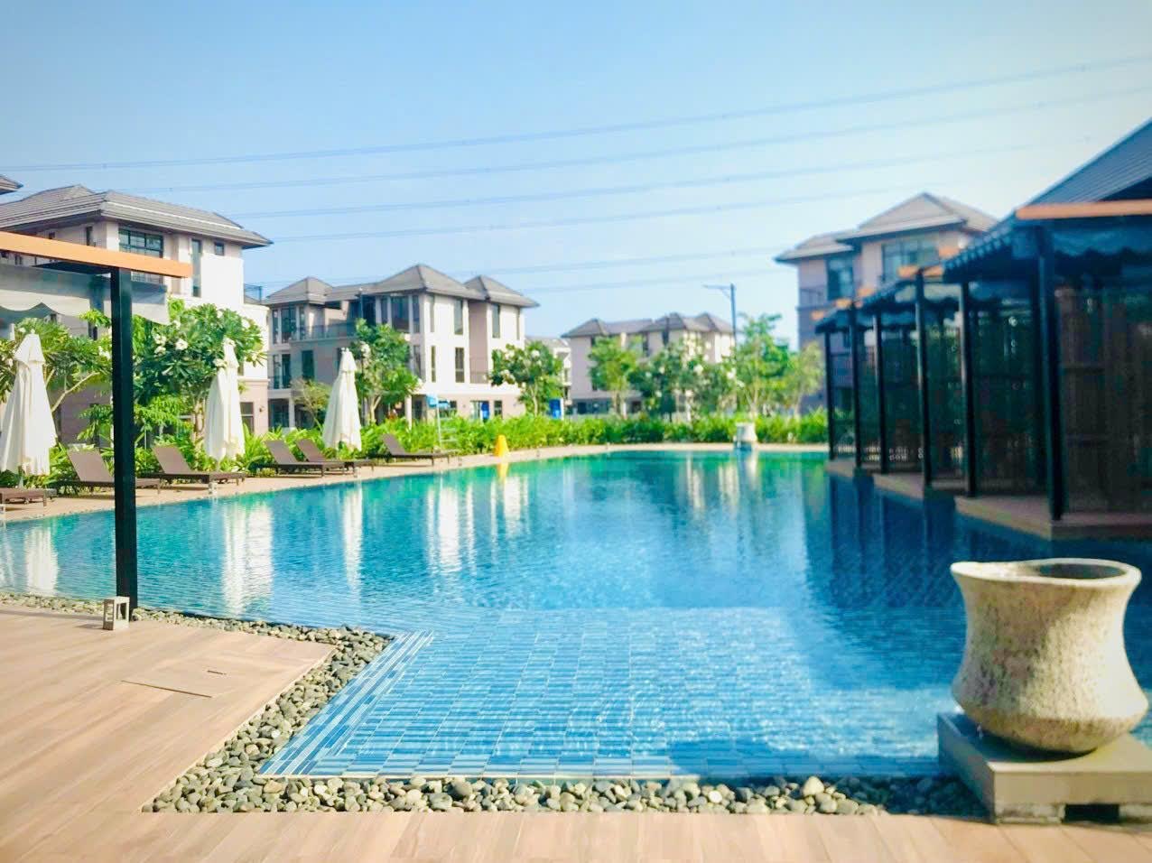 Hồ bơi clubhouse với ghế tắm nắng và cabana tại GS Metrocity Nhà Bè