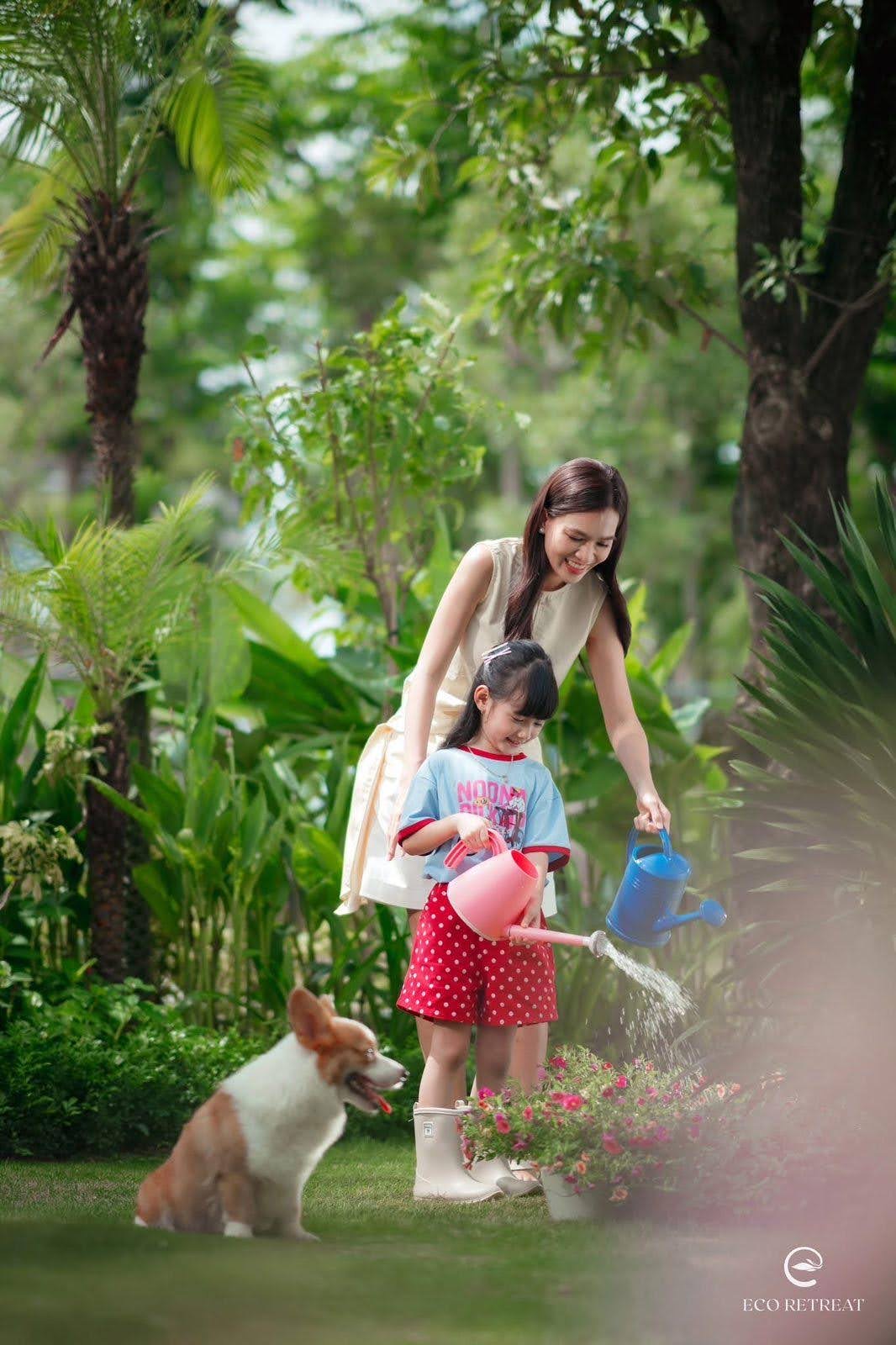 Mẹ và bé tưới cây trong khu vườn cùng chú chó