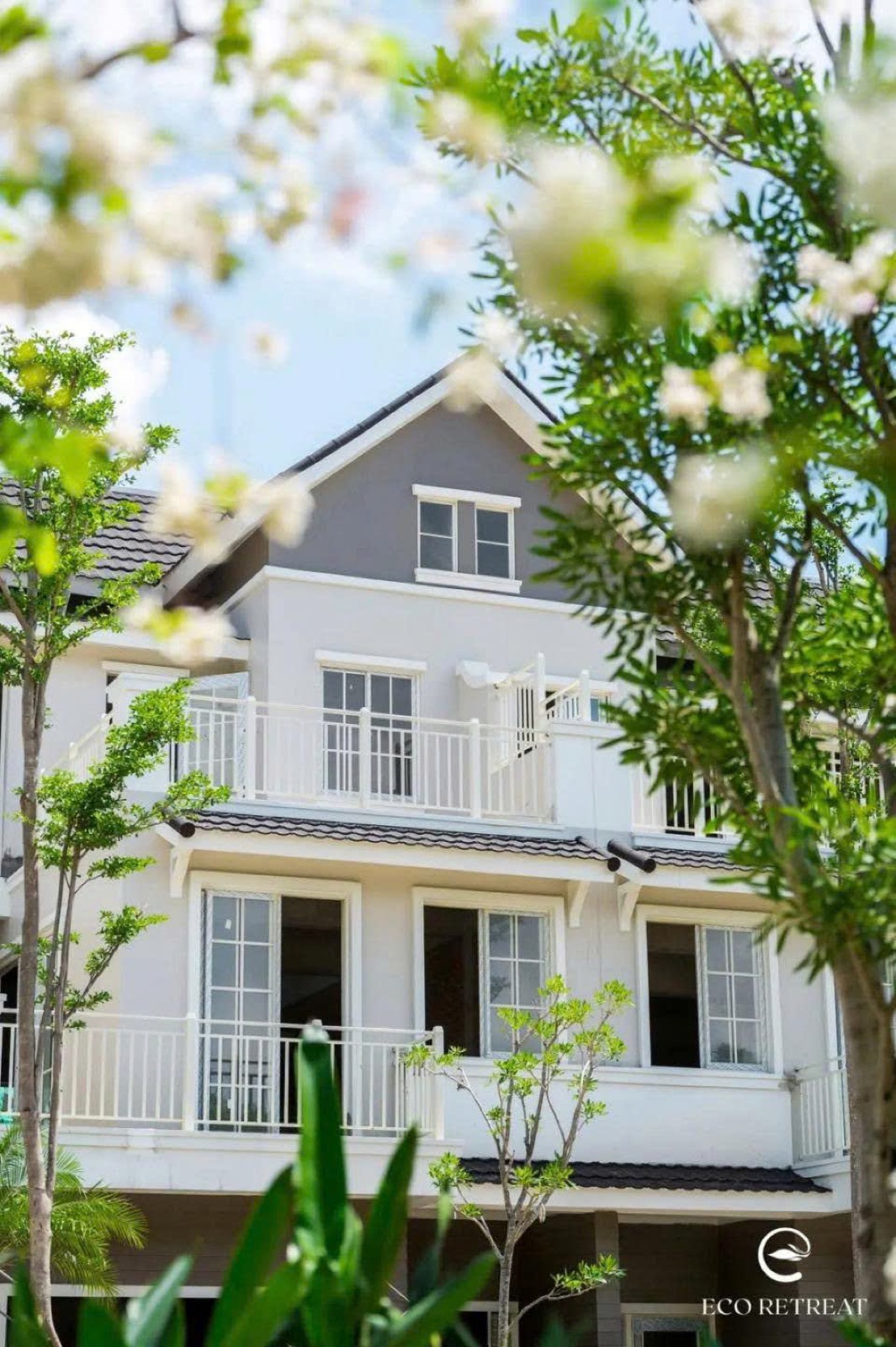 Mặt tiền nhà Home Retreat với ban công trắng giữa hoa lá