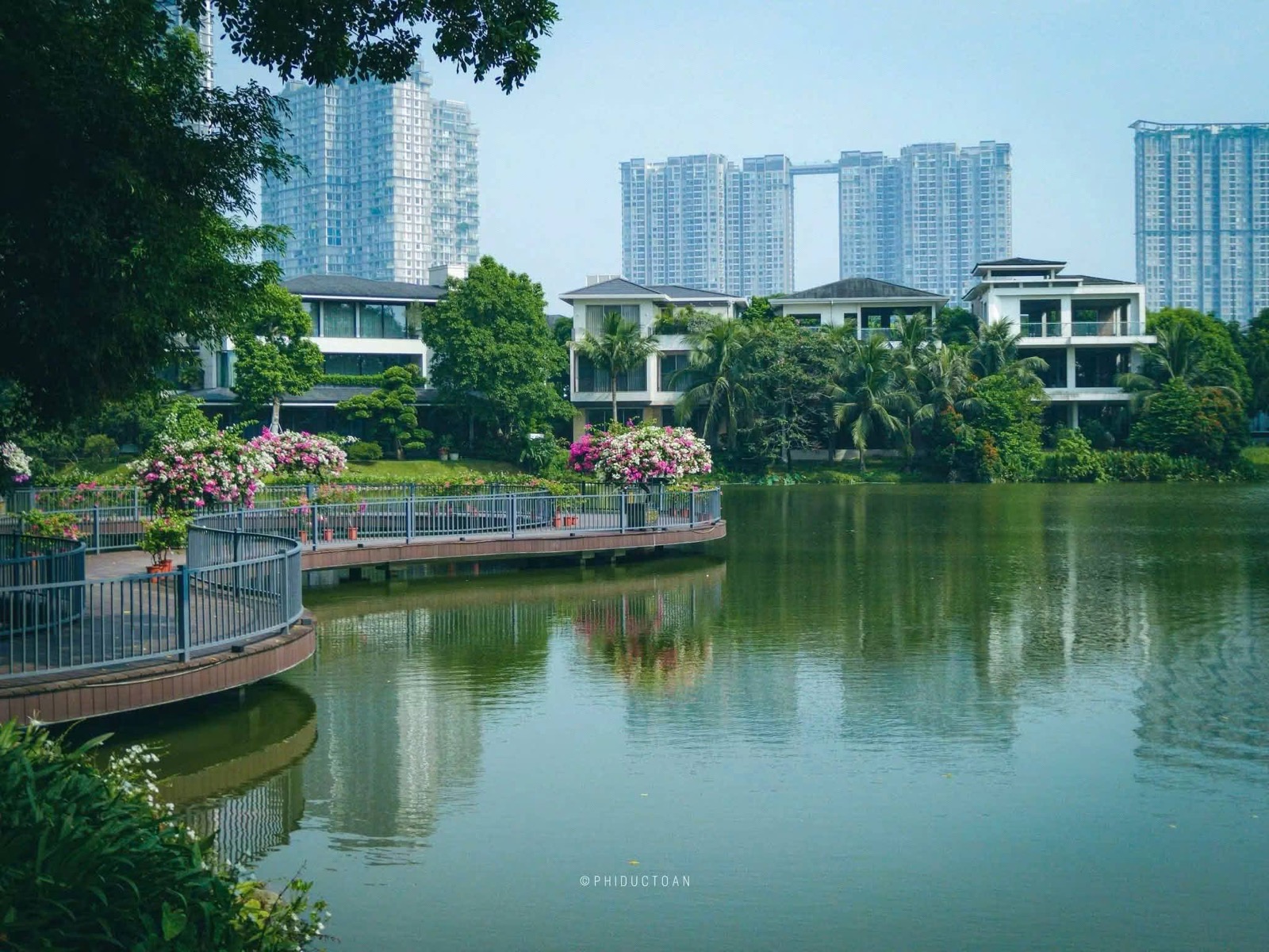 Lối đi ven hồ với những chậu hoa giấy, phía sau là các tòa căn hộ
